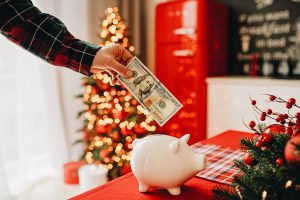Man putting a 100 dollar bill into a piggy bank during Christmas