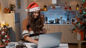 Young woman wearing a Santa hat buying gifts online